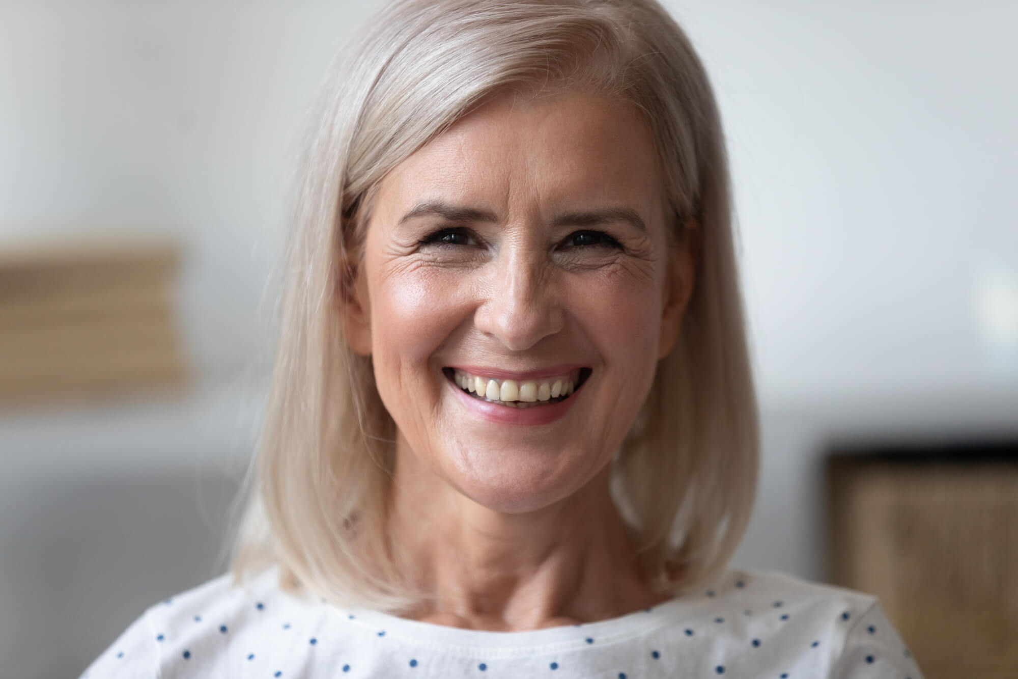 Close up portrait middle-aged blond woman looks at camera posing indoors feels happy